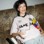 CARMEN PORTE UN COLLIER TASAKI : DANGER FANG EN OR JAUNE 18 CARATS, PERLES AKOYA ET DIAMANTS. T-SHIRT HUGO EN MESH INSPIRÉ DU FOOTBALL. SHORT UNIQLO EN MELTON SAC CHANEL SAC ROSE ET BLANC EN DENIM IMPRIMÉ ET MÉTAL. 1NSTANT STYLE