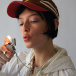 CARMEN PORTE UNE CHEVALIÈRE ARTHUS BERTRAND PAVÉE DIAMANTS EN OR JAUNE 18 CARATS ET DIAMANTS. COLLIER BRIQUET ARGENTÉ S.T. DUPONT ENSEMBLE CHANEL DE JOGGING BAS ET VESTE TAFFETA DE SOIE CASQUETTE BOBO CHOSES.