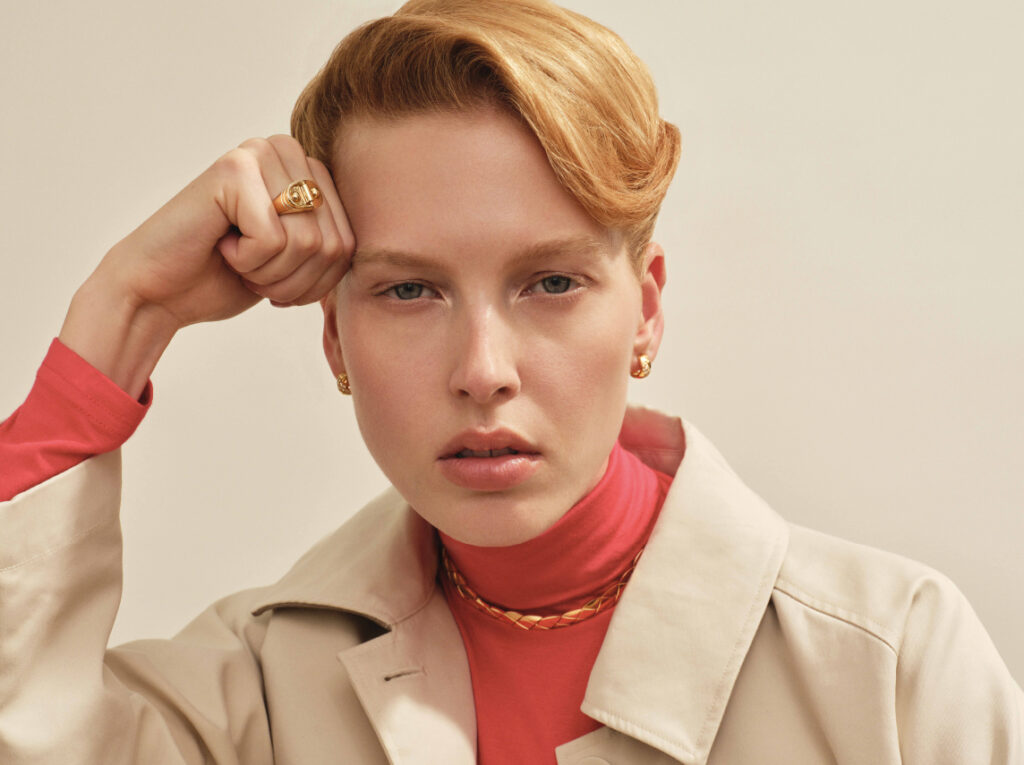 Chanel Joaillerie :Choker souple COCO CRUSH, motif matelassé, en or jaune 18K et Boucles d’oreilles COCO CRUSH, motif matelassé, en or jaune 18K et diamants. Chanel Joaillerie. Statement: Bague chevalière Rivet en or jaune. Trench Officine Générale.